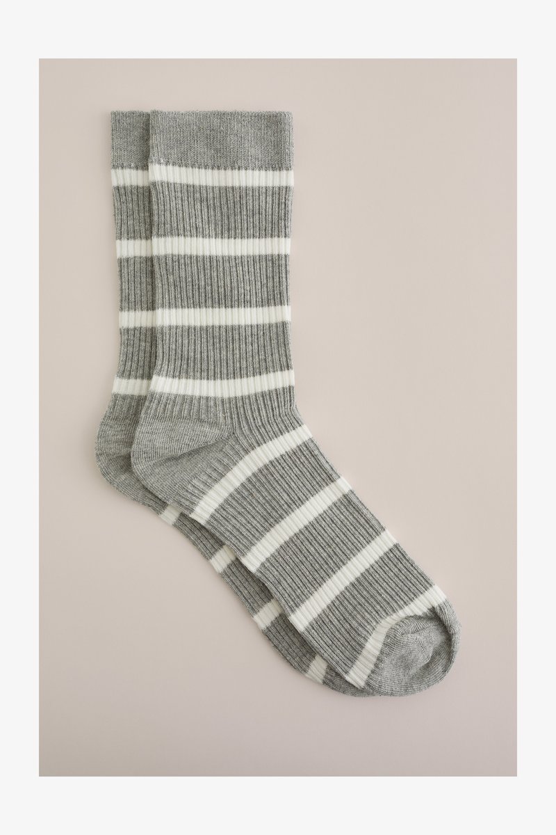 Calcetines de rayas grises y blancos con una textura acanalada, que presentan franjas horizontales alternando entre gruesas y finas.