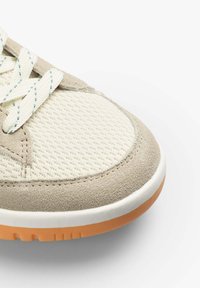 Sneaker mit einem atmungsaktiven, cremefarbenen Mesh-Obermaterial und grauen Wildleder-Akzenten. Weiße Gummi-Mittelsohle und strukturierte, orangefarbene Außensohle. Blaue Schnürsenkel.