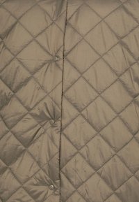 Quilted puffer jacket in muted tan with diamond pattern, featuring rounded buttons along the front, smooth texture, and subtle sheen.