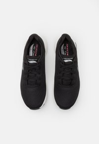 Juodi Skechers Arch Fit batai pagaminti iš tinklinės medžiagos, su raištelių užsegimu, tekstūruotu paviršiumi ir baltu padu.
