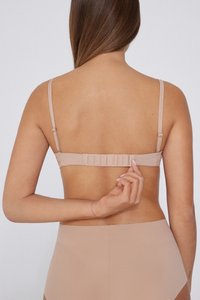 Sujeción nude vista desde la parte posterior, con tirantes ajustables, un cierre de gancho y ojal, y una textura de tela suave.
