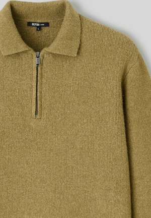 Pull-over vert olive à texture côtelée, col à demi-fermeture éclair et étiquette BZB. Présente des manches longues et une coupe ample.