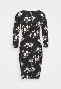 Robe noire ajustée à manches longues, motif floral avec des fleurs blanches et beiges, mi-longue, avec une fermeture éclair dans le dos.