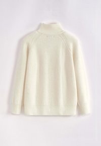 Pull en tricot couleur crème avec un col haut, des manches raglan et une texture côtelée. Il présente une coupe décontractée et des fentes sur les côtés à l'ourlet.
