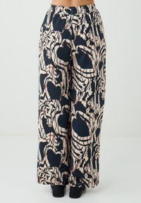 Wijdvallende broek met een bloemmotief; marinblok en crème kleuren met abstracte vormen. Heeft een elastische tailleband en lichte stof.