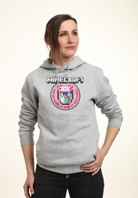 Felpa grigia realizzata in misto cotone, presenta una grafica rotonda con un personaggio pixelato e testo in nero e rosa. Polsini e orlo a coste.