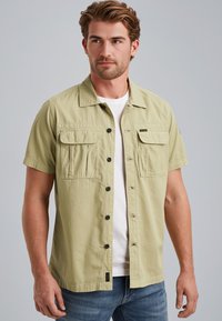 Short-sleeve shirt in light green, made of fabric with a smooth texture. Features two chest pockets, a button front, and a collar.