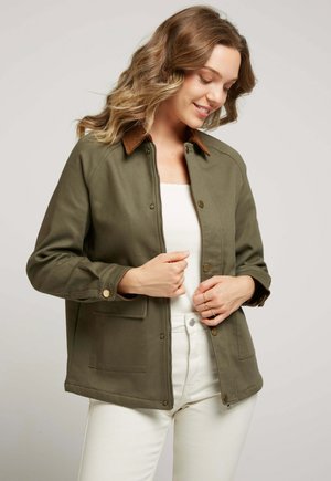 Veste olive avec un col marron, boutons-pression et deux poches à l'avant. Design décontracté, mi-long, texture du tissu visible.