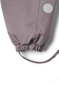 Szürke szövetkabát mandzsetta rugalmas húzózsinórral. Fehér kontrasztos kör alakú logó folttal díszítve. Simább textúra.