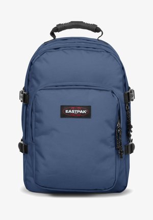 Mochila Eastpak azul hecha de un tejido duradero que cuenta con un asa superior, correas ajustables, un bolsillo frontal y una insignia negra en la parte delantera.