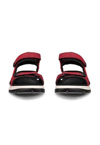 Pari punaisia ja mustia avokkaisia urheilutossuja, joissa säädettävät hihnat ja valko-mustat kumipohjat, nähtynä edestä.