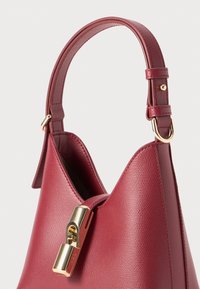 Sac à main en cuir bourgogne avec une forme structurée, rehaussé d'une fermeture à verrou doré et d'une courte sangle au toucher doux.