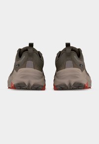 Ζευγάρι καφέ και γκρι παπούτσια πεζοπορίας με χοντρές σόλες και κόκκινα διακοσμητικά στοιχεία, εμφανιζόμενα από πίσω σε λευκό φόντο.