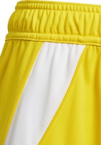 Gele sportshorts met een witte diagonale paneel, elastische tailleband en een zachte textuur. Kenmerkt zich door contrasterende stiksels langs de naden.