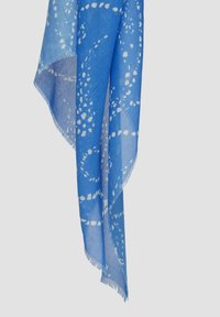 Écharpe bleue en tissu léger, ornée de motifs circulaires blancs, avec des bords frangés et une apparence douce et texturée.