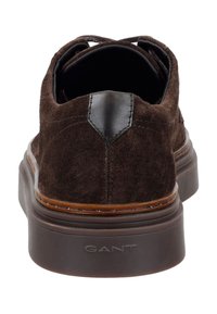 Hnědé semišové volnočasové boty s hladkým černým koženým podpatkem a silnou hnědou gumovou podrážkou, se švy pro větší odolnost.