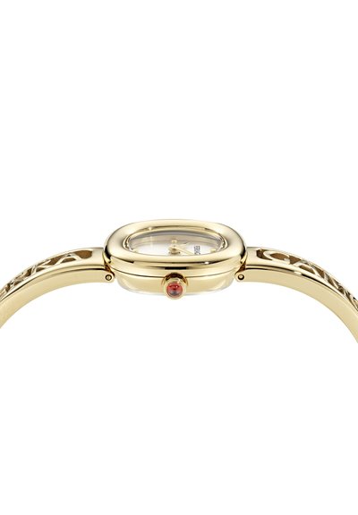 Montre en métal doré avec un boîtier ovale et un bracelet à motif, dotée d'un cadran transparent et d'une accent rouge sur la couronne.