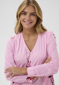 Pink gestreifte Bluse mit V-Ausschnitt und floralen Akzenten. Der leichte Stoff hat lange Ärmel mit gerafften Schultern.