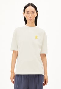 Korte mouwen crèmekleurig T-shirt van katoen, met een geel lintlogo op de linkerkant van de borst. Rechte zoom en een ontspannen pasvorm.