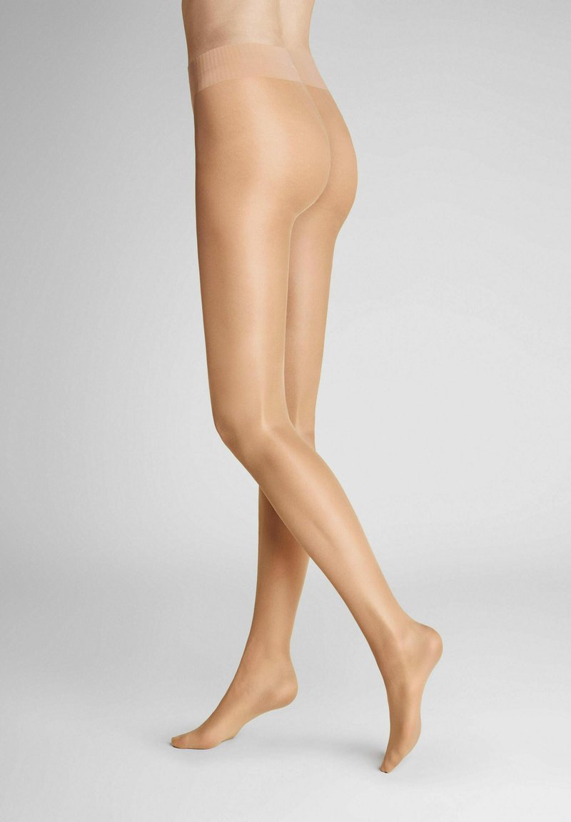 Nude sheer tights with a smooth texture, semi-matte finish, and a wide, elastic waistband. Legs positioned at an angle, foot bare.
