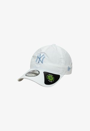 White baseball cap made of fabric, featuring a light blue embroidered logo on the front, adjustable strap, and black sticker on the side.