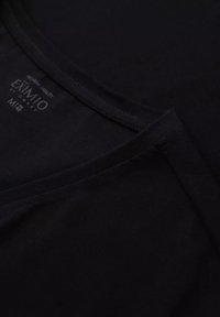 Czarny bawełniany T-shirt z dekoltem w serek, szyty dekolt i akcenty na końcówkach, oraz metka wskazująca markę "EXIMIO" i rozmiar M.