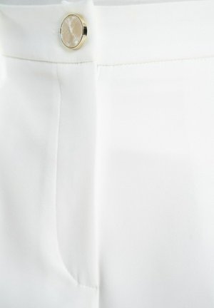 Białe spodnie o dopasowanym kroju, charakteryzujące się gładką teksturą, pionowymi szwami oraz błyszczącym, okrągłym guzikiem przy talii.