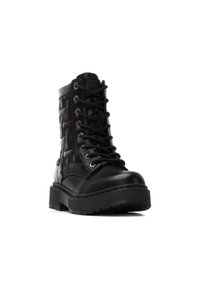 Botín negro con cordones, hecho de cuero suave y tejido texturizado, con una suela de goma gruesa y ojales metálicos para los cordones.