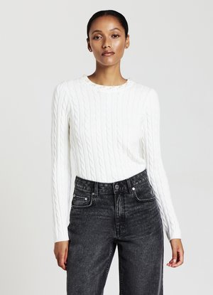 Weißer Strickpullover mit Kabelmuster, rundem Halsausschnitt mit Perlenakzenten und langen Ärmeln, kombiniert mit grauen hochtaillierten Jeans.