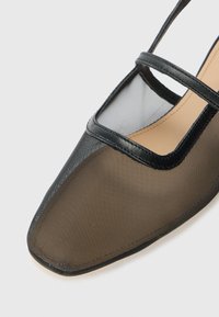 Black synthetic shoes with a square toe, mesh upper, and a slender strap across the instep. Features a smooth, textured finish.