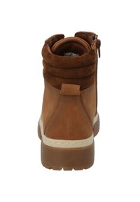 Botines de ante marrón con la parte superior caída, que cuentan con un cierre de cremallera, suela de goma texturizada y detalles de costura a lo largo del borde.