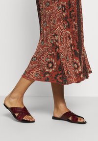 Bordeaux slip-on sandalen met een kruisbandontwerp, gemaakt van faux krokodillenleer. Vlakke zool en open teenstijl.