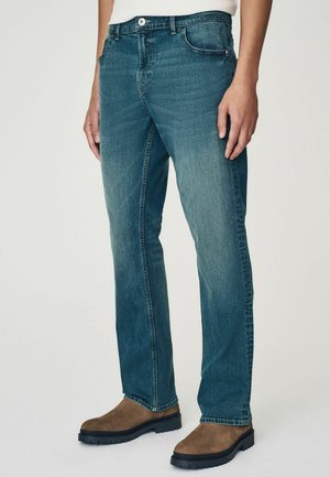 Jeans din denim albastru cu un croi drept, având design cu cinci buzunare și o spălare deschisă. Țesătura are o textură subtilă și o ușoară decolorare.