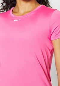 Camiseta deportiva rosa con cuello redondo y mangas cortas. Fabricada en tejido suave, con un pequeño logo de Nike en blanco en el pecho.
