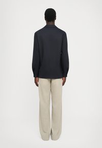 Námornícka polokošeľa s dlhým rukávom a golierom, s detailom zadného skladania, a béžové široké nohavice vyrobené z textúrovanej látky. Jednoduchý štýl, strih na mieru.