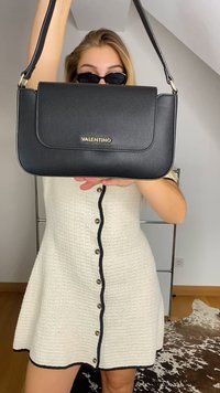 Melnas ādas rokassoma ar gludu apdari, taisnstūra forma, lāpsta ar aizdari un zelta "Valentino" logo. Redzama regulējama plecu siksna.