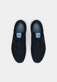 Juodos Tommy Hilfiger tinklelio sportbačiai su baltais padais, juodomis raištelėmis ir mėlynomis vidpadžiais, ant kurių matoma prekės ženklo pavadinimas.