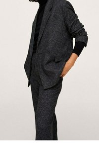 Donkergrijze op maat gemaakte pak met een gestructureerde stof, voorzien van een blazer met één knoop en taps toelopende broek, beide met een subtiele glans.