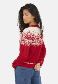 Maglione rosso lavorato a maglia con motivo Fair Isle bianco nella parte superiore, caratterizzato da una trama a trecce e polsini e orlo a coste.