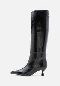 Botas de cuero negras hasta la rodilla con un acabado brillante, punta afilada y un pequeño tacón cuadrado. Textura suave, detalles de costura mínimos.