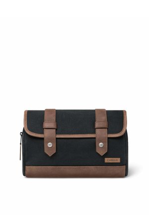 Schwarzes Canvas und braune Leder-Kulturtasche mit zwei vorderen Riemen, Druckknöpfen, Reißverschluss an der Seite und Cabaia Markenlabel vorne unten rechts.