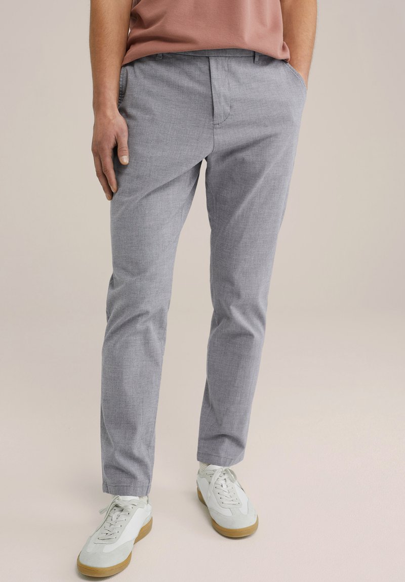 Pelēki, piegriezti bikses, izgatavotas no viegla auduma ar smalku tekstūru; tām ir jostas cilpas un kabatas, apvienotas ar ikdienišķiem baltajiem sporta apaviem.