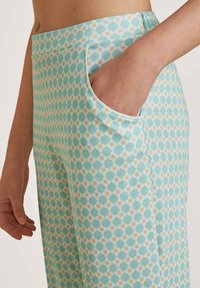 Patronen broek in lichtturquoise met diamondvormen in pasteloranje en wit. Beschikt over een zijzak en een zachte, rekbare stof.