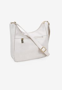 Bolso de hombro de cuero en suave blanco, con un diseño curvado, correa ajustable y detalles en tono dorado en la cremallera, además de un bolsillo exterior.