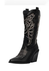 Botas de vaquero de cuero negro con puntera afilada, tacón alto y patrones de costura blanca intrincados que representan plumas y remolinos. Diseñadas para un ajuste ceñido.