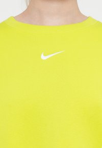 Svetlozelena dukserica s rebrastim ovratnikom, napravljena od pamuka, s malim belim Nike logotipom na grudima.