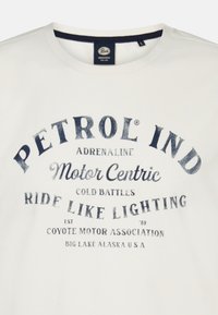 Hvid bomulds T-shirt med marineblå trykte tekster og grafikker, herunder "PETROL IND" og "RIDE LIKE LIGHTNING." Normal pasform med rund hals.