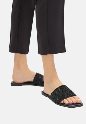 Infradito neri con suola piatta, decorati con piccole strass sulla fascia superiore. Design open-toe con texture morbida.