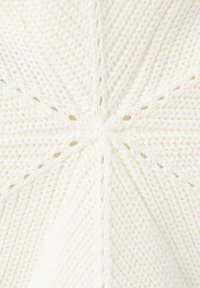 Tissu tricoté blanc avec un motif radial formé par des rangées alternées de mailles texturées et ouvertes convergeant au centre.