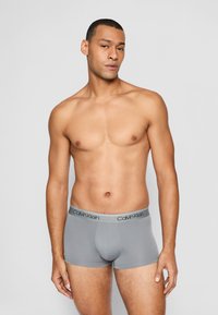 Graue Baumwoll-Boxershorts mit weichem, elastischem Bund, der das "Calvin Klein"-Logo trägt, glatter Oberfläche und figurbetontem Design.